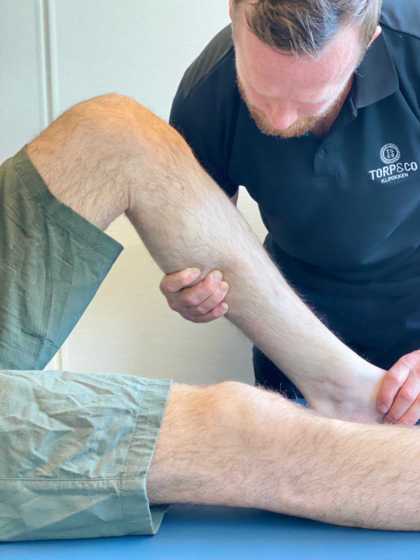 Behandler undersøker og holder rundt leggen til en person med beinhinnebetennelse