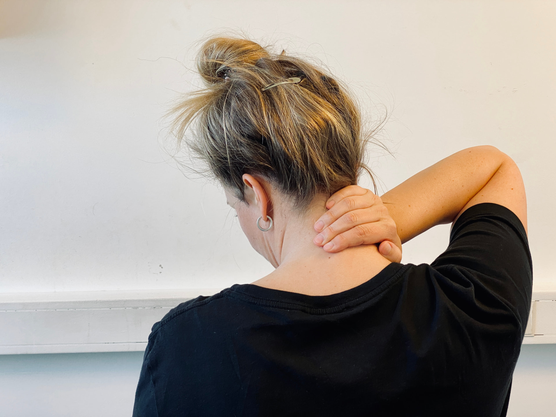 Person holder seg på nakken med hånden fra bak